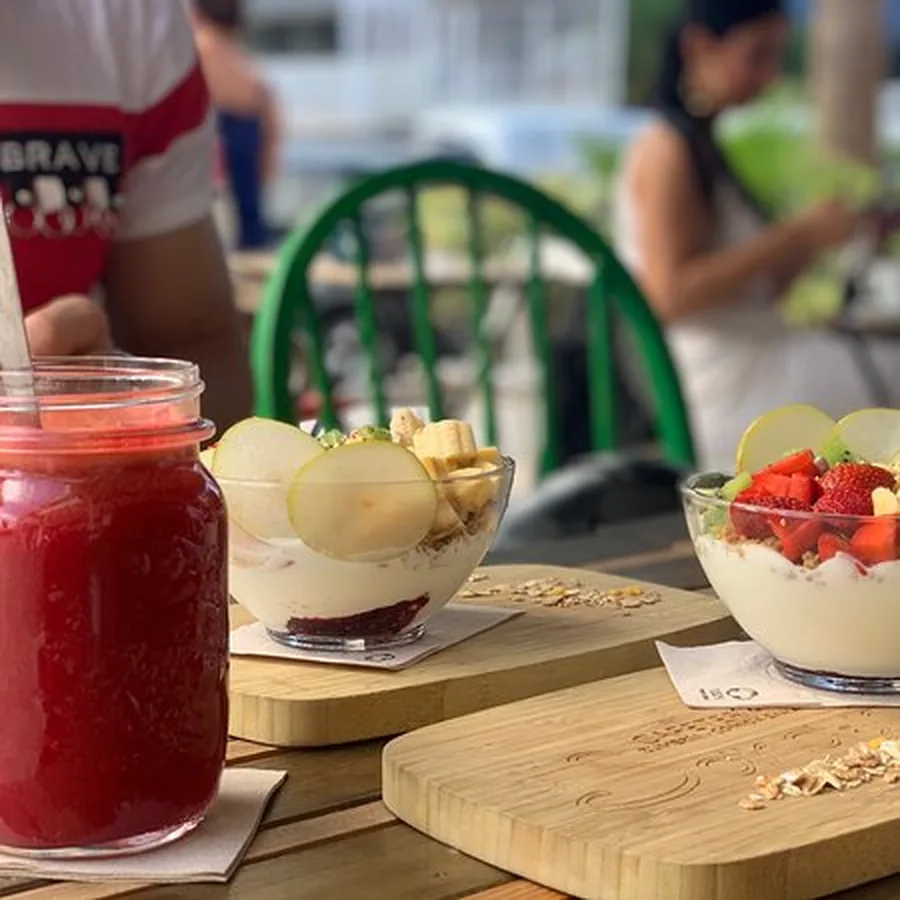 Zumo rojo de frutos del bosque en tarro junto a bowls de yogur en la terraza