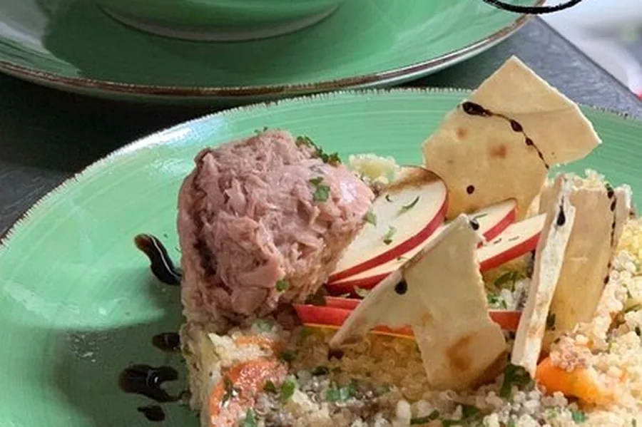 Quinoa con atún, manzana y crujiente de pan en plato verde